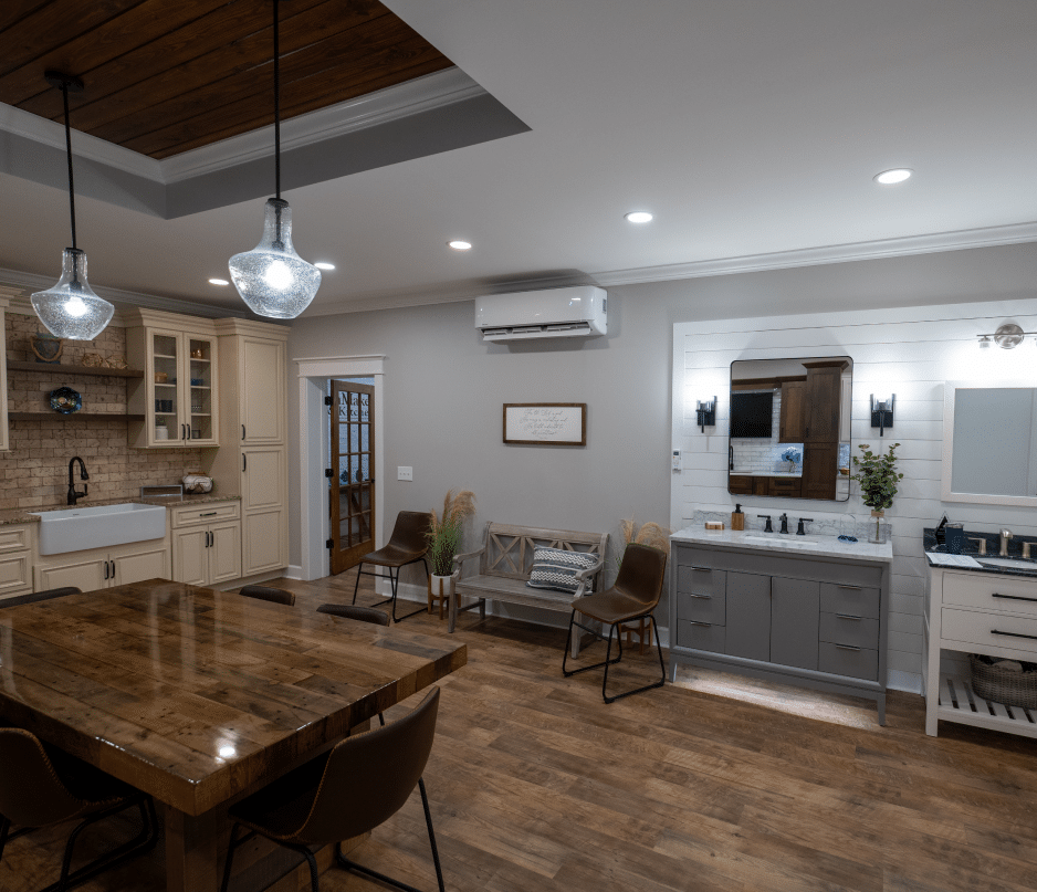 Spacious, well-lit room with rustic wooden dining table, modern kitchen, bathroom vanity and large mirror; cozy decor throughout.